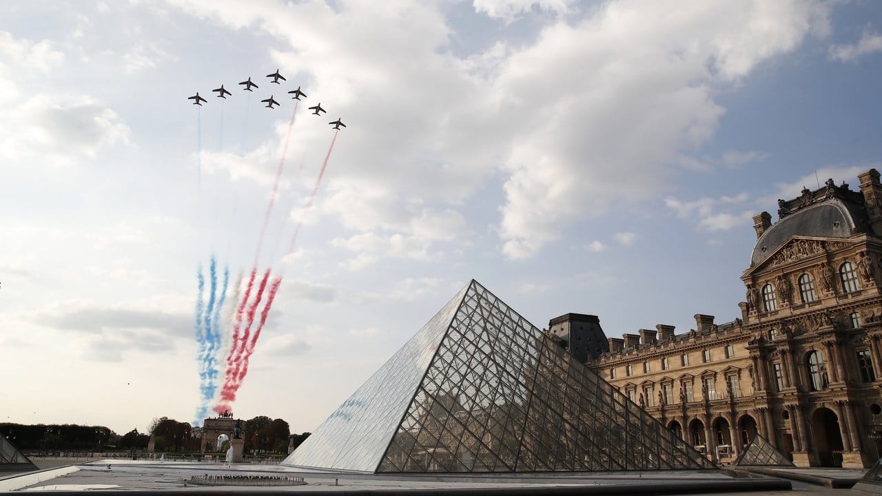 Flugzeuge der Kunstflugstaffel "Patrouille de France" zeichnen die französische Nationalflagge über dem Museum Louvre an den Himmel.