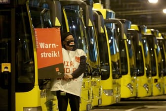 Ein streikender Busfahrer der Ruhrbahn klebt ein Plakat "Warnstreik" an einen Bus.