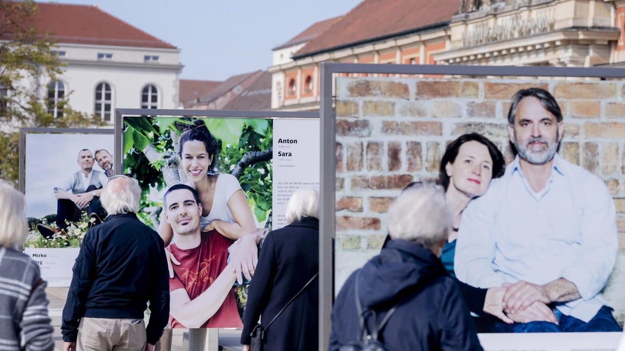 Besucher schauen sich in Potsdam die Fotoausstellung "30 Jahre – 30 Paare" an, welche Teil der Freiluftausstellung EinheitsEXPO ist.
