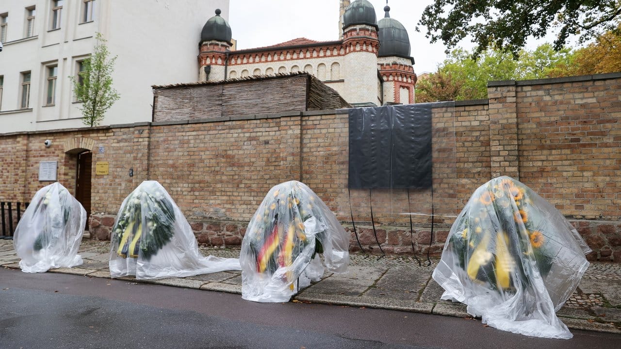 Die Kränze für den Gedenktag an den Anschlag in Halle stehen mit Regenfolie überzogen vor der Synagoge.