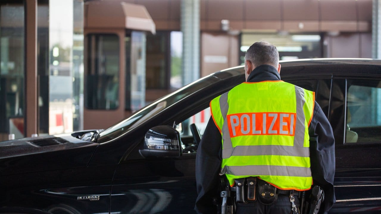 Ein Beamter der Bundespolizei kontrolliert an einem Grenzübergang einen Autofahrer. Ein Beamter der Bundespolizei kontrolliert an einem Grenzübergang einen Autofahrer.