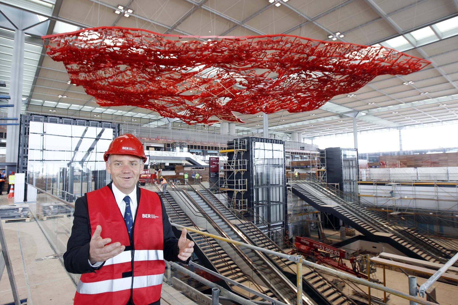 Auch Flughafenchef Rainer Schwarz ist im April 2012 ganz begeistert von der großen Halle des BER mit der markanten Kunst an der Decke. Schon bald, so hofft er da noch, werden hier die ersten Linienflüge abgefertigt.