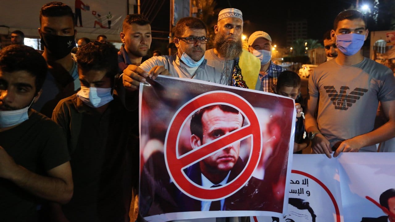 Ein Palästinenser hält bei einer Protestaktion in den palästinensischen Autonomiegebieten ein Anti-Macron-Plakat.