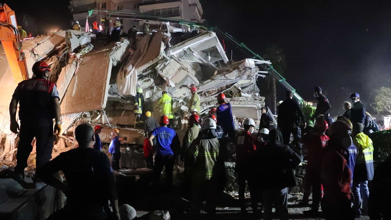 Rettungskräfte versuchen Menschen zu befreien, die unter den Trümmern eines Gebäudes in Izmir sind.