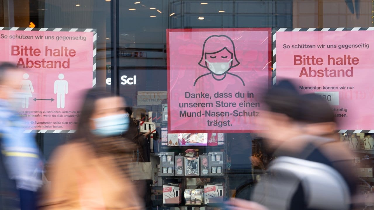 Hinweisschilder zum Corona-Schutz an einem Schaufenster in der Innenstadt von München.