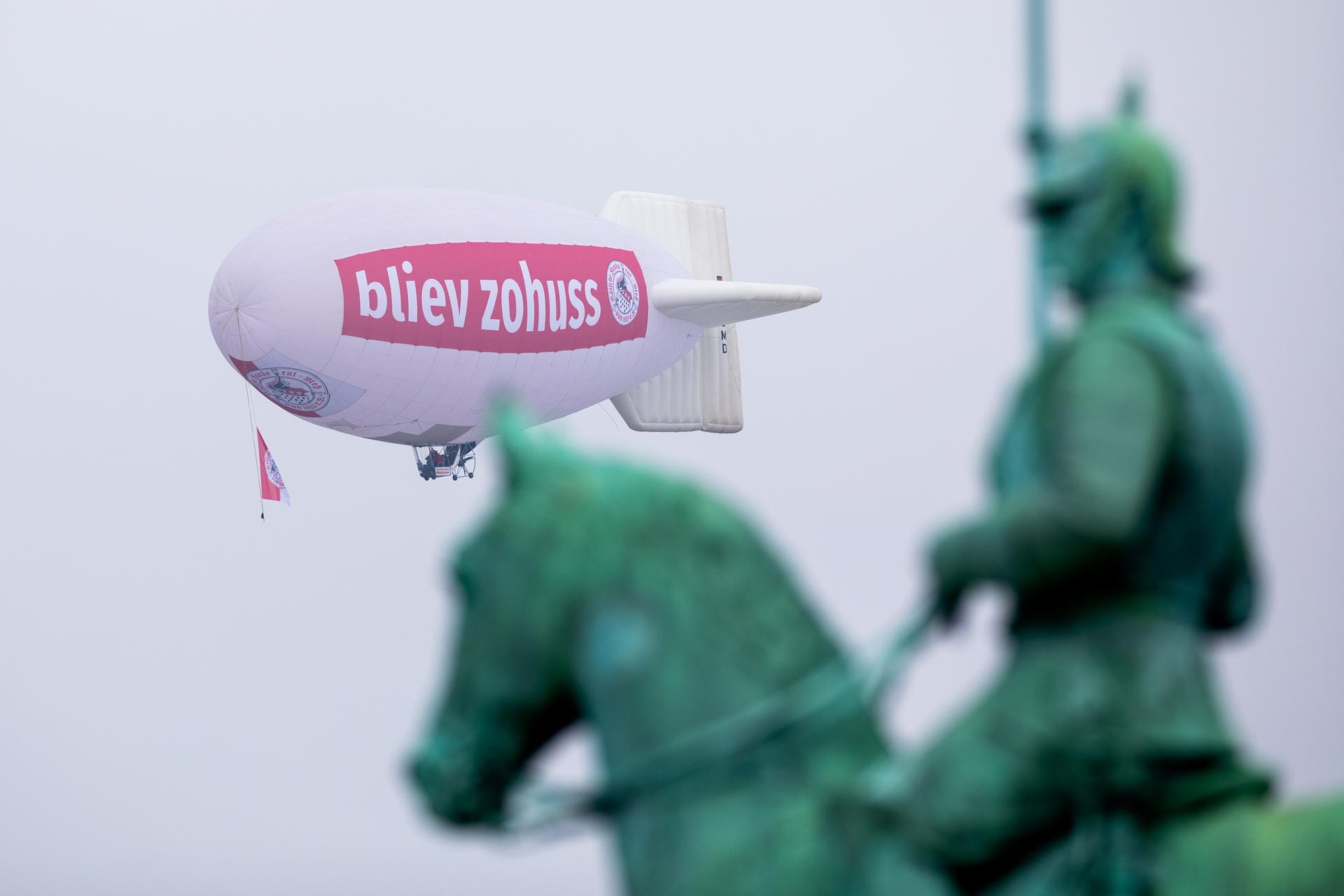 Ein Zeppelin mit der Aufschrift «bliev zohuss» (Bleib zu Hause) der Roten Funken fliegt hinter dem Reiterdenkmal am Himmel: Die Kölner waren aufgerufen, am 11.11. den Karnevalsauftakt nicht zu feiern.
