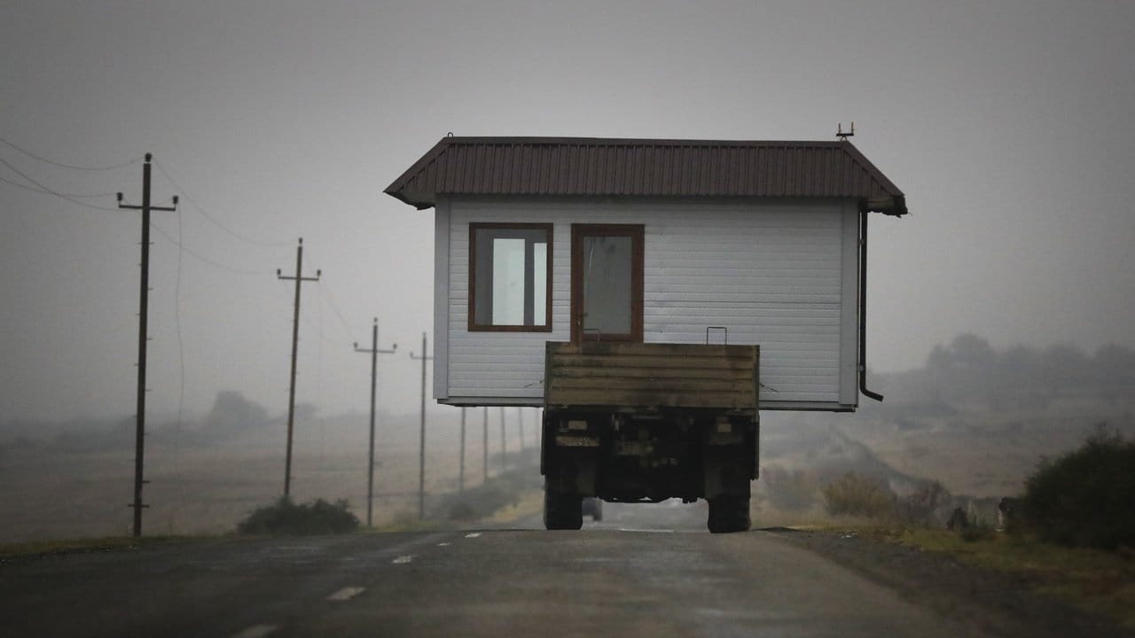 Eine Familie befördert ihr kleines Haus auf einem Lastwagen, als sie ihr Heimatdorf in der Region Berg-Karabach verlassen.