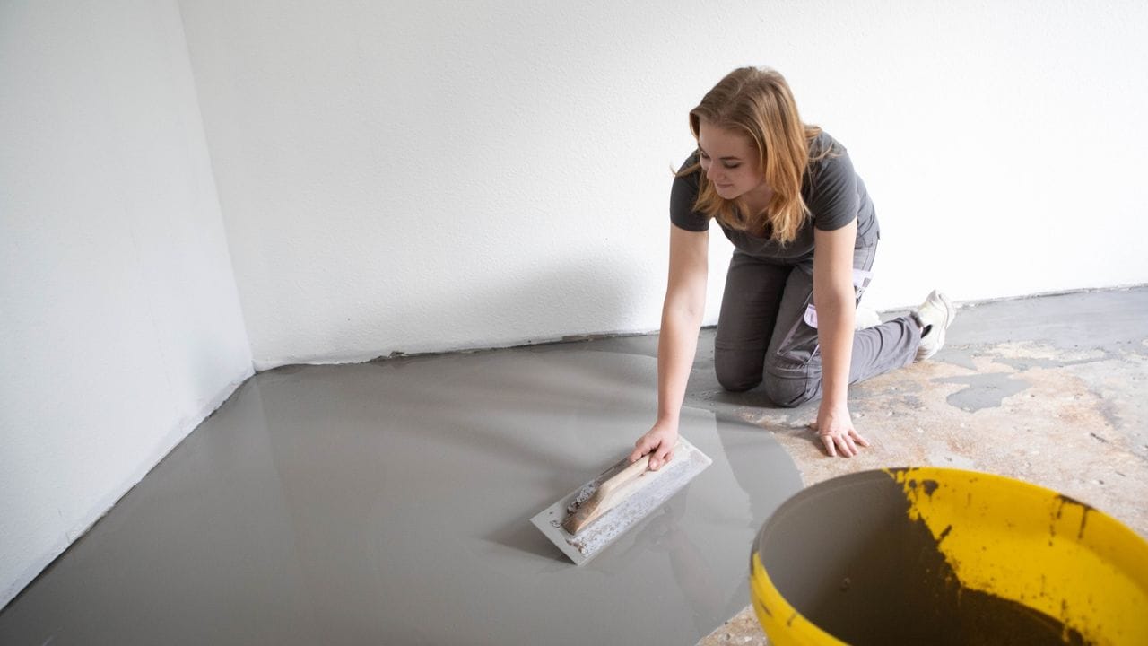 Raumausstatter machen sich schonmal die Hände schmutzig: Hannah Hofstätter spachtelt den Untergrund zur Vorbereitung.