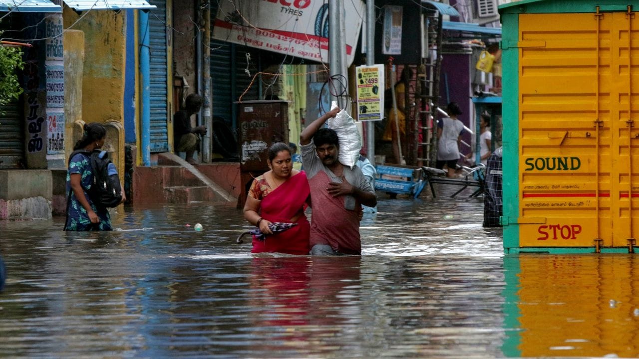 Menschen waten durch eine überflutete Straße in Chennai.