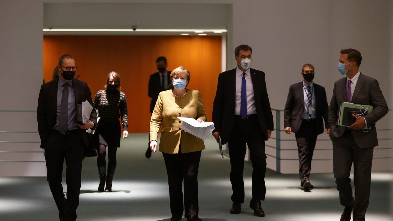 Kanzlerin Angela Merkel (M) schreitet mit Ländervertretern zur Pressekonferenz, um die Corona-Ergebnisse vorzustellen.