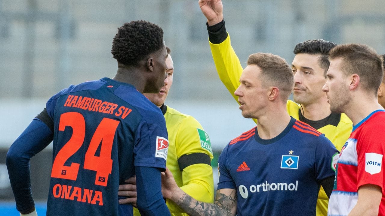 Hamburgs Amadou Onana (l) sieht von Schiedsrichter Florian Badstübner die Gelbe Karte.