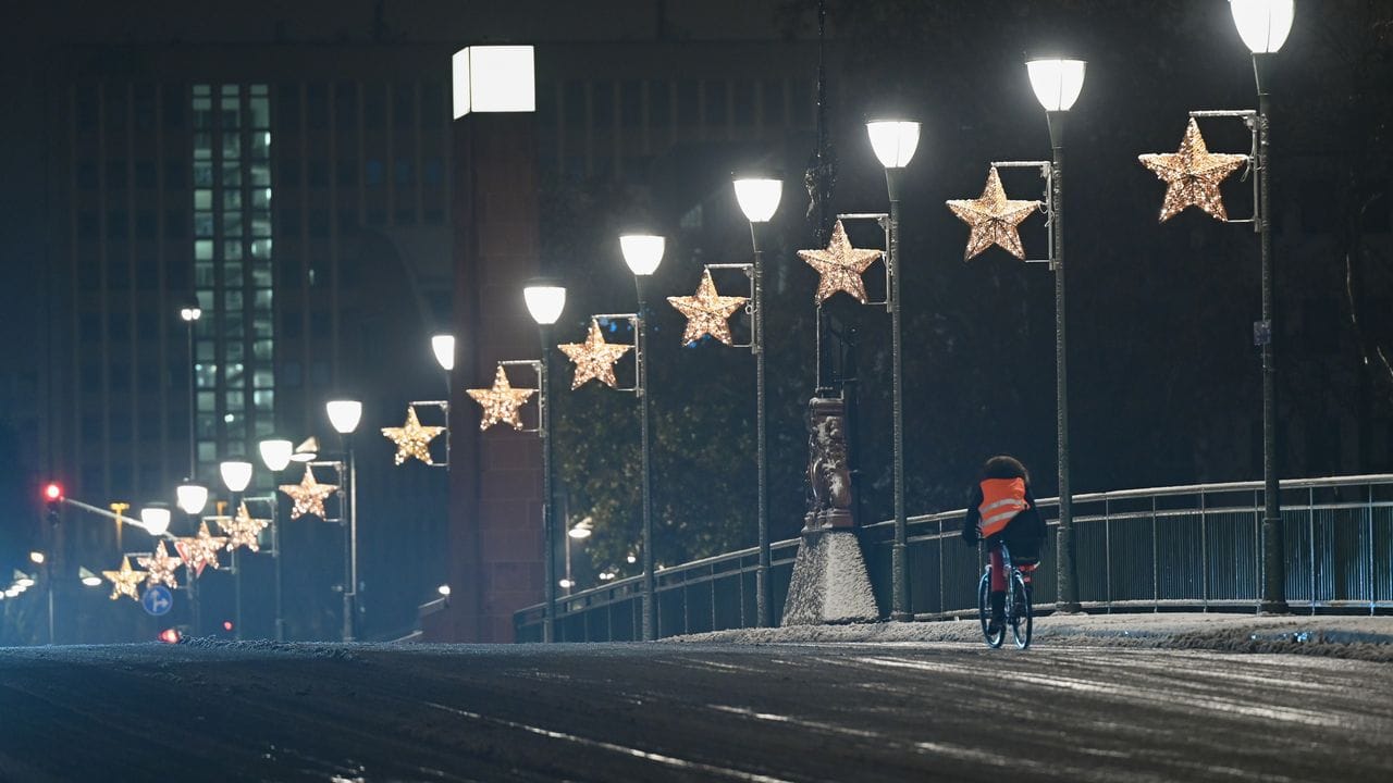 Ein Radfahrer ist nach einem Wintereinbruch in der Nacht auf der Alten Brücke in Frankfurt unterwegs.
