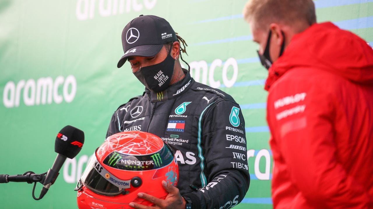 Mick Schumacher überreicht auf dem Nürburgring Lewis Hamilton (l) einen Helm seines Vaters Michael.