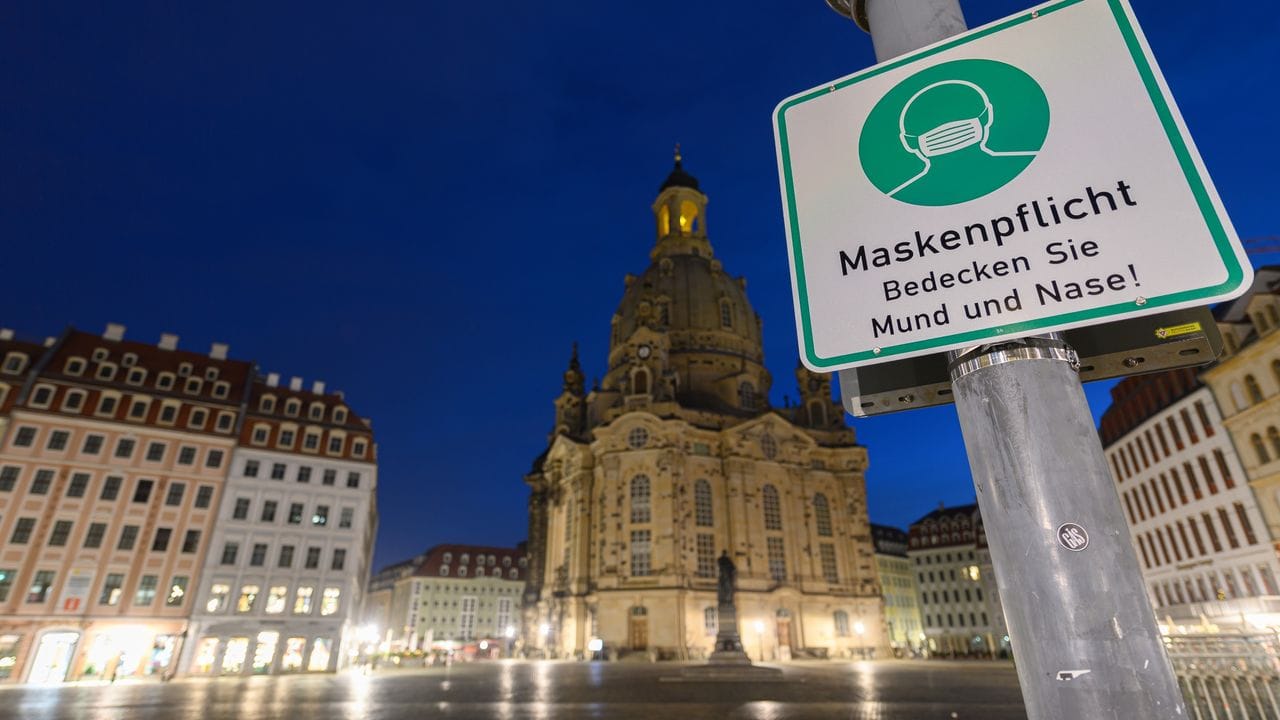 Ein Hinweisschild auf die Maskenpflicht hängt auf dem Neumarkt vor der Frauenkirche an einem Lampenmast. Ein Hinweisschild auf die Maskenpflicht hängt auf dem Neumarkt vor der Frauenkirche an einem Lampenmast.