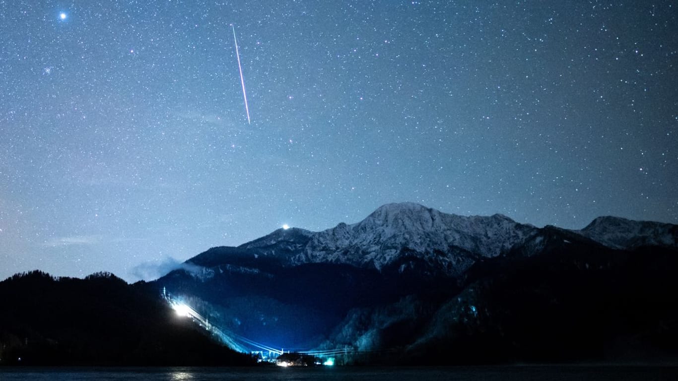 Eine Sternschnuppe ist während des Geminiden-Meteteorstroms am Sternenhimmel über dem Kochelsee zu sehen.