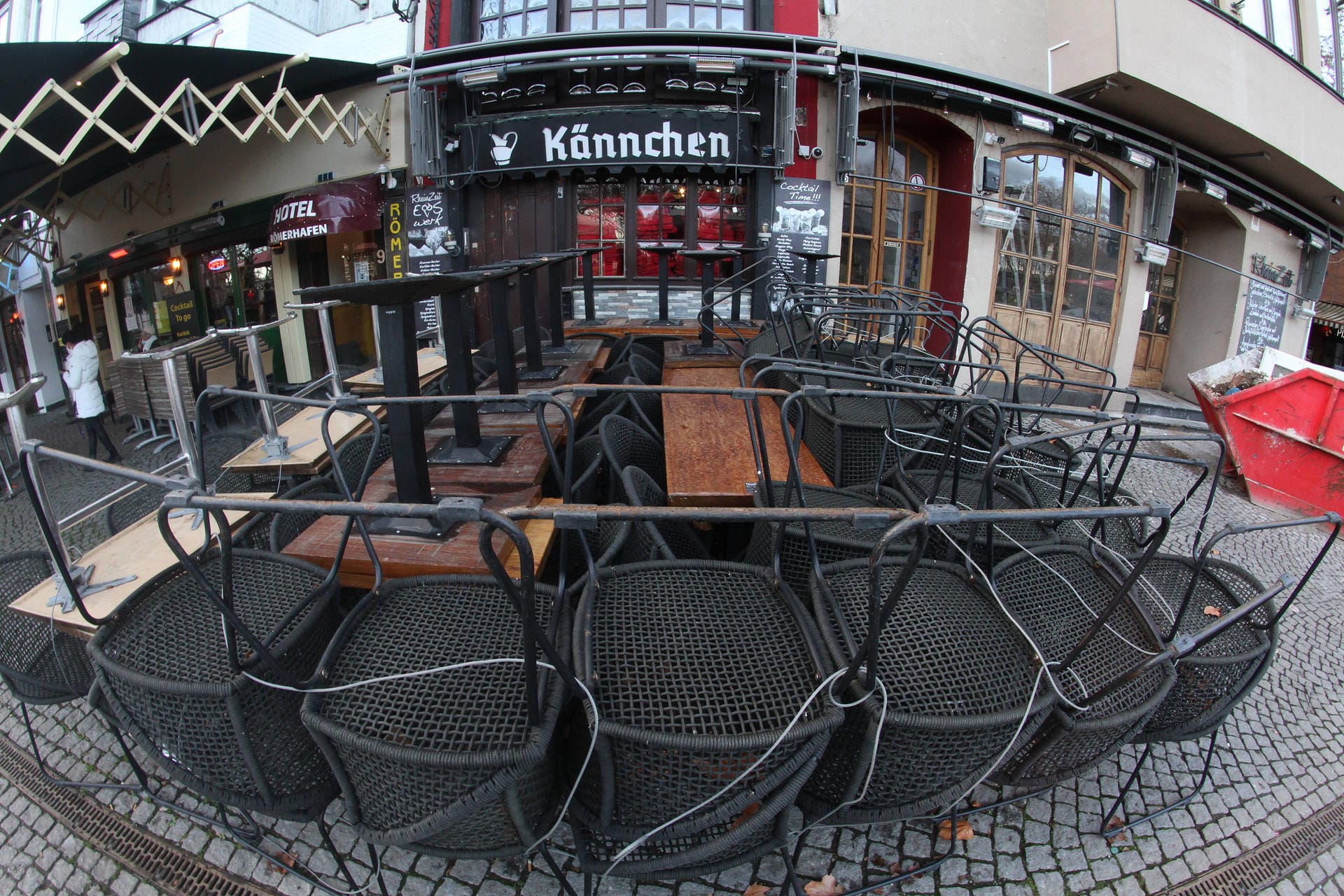 Eine geschlossene Gaststätte in der Altstadt von Köln hat Tische und Stühle mit Drahtseilen gesichert.