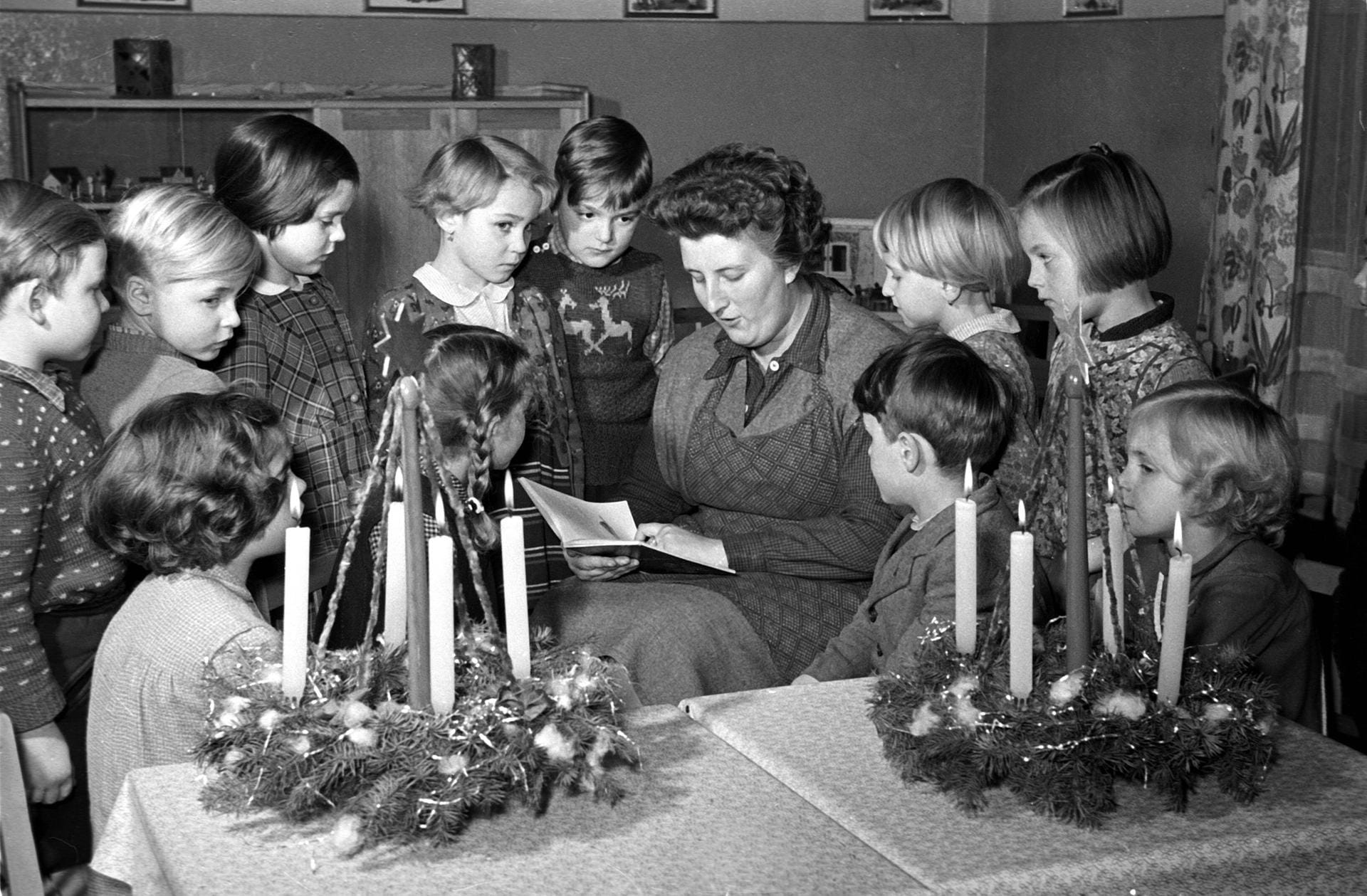 Weihnachten 1956: Eine Erzieherin liest Kindern aus einem Weihnachtsbuch vor.