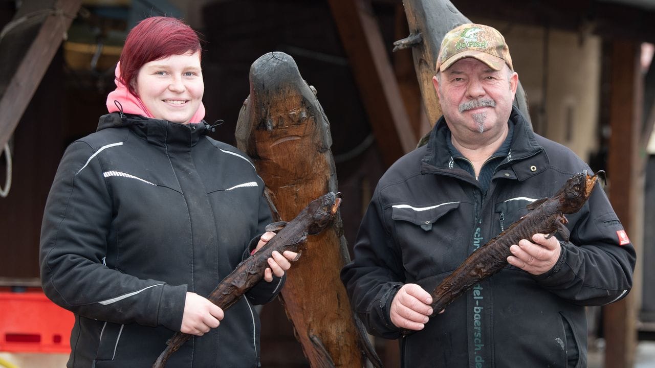 Armin Kittner, Teichwirt, und seine Tochter Emma halten auf dem Gelände der Teichwirtschaft Petershain jeweils eine geräucherte Quappe. Armin Kittner, Teichwirt, und seine Tochter Emma halten auf dem Gelände der Teichwirtschaft Petershain jeweils eine geräucherte Quappe.