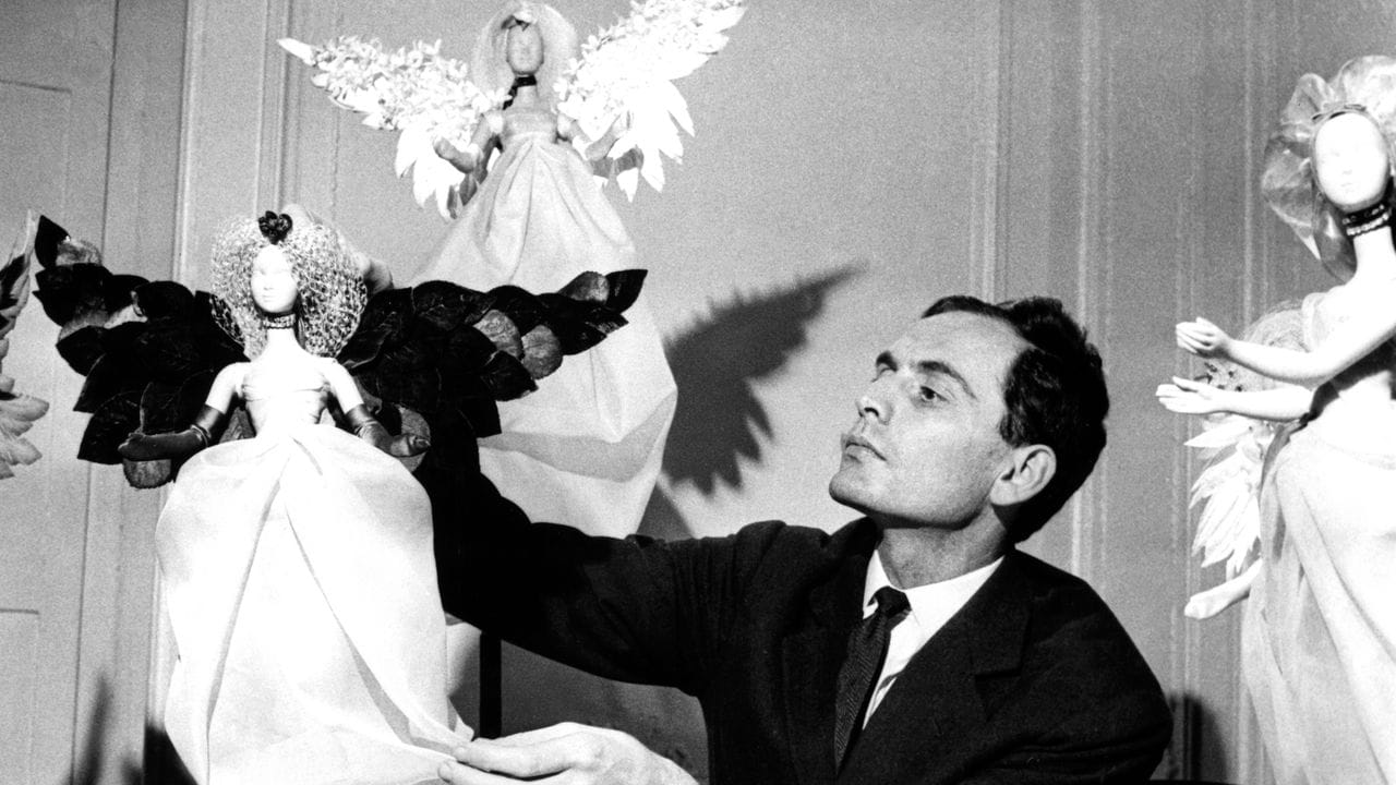 Pierre Cardin mit festlich gekleideten Puppen, die in der Vorweihnachtszeit an den Wänden seines Salons aufgestellt wurden (1958). Pierre Cardin mit festlich gekleideten Puppen, die in der Vorweihnachtszeit an den Wänden seines Salons aufgestellt wurden (1958).