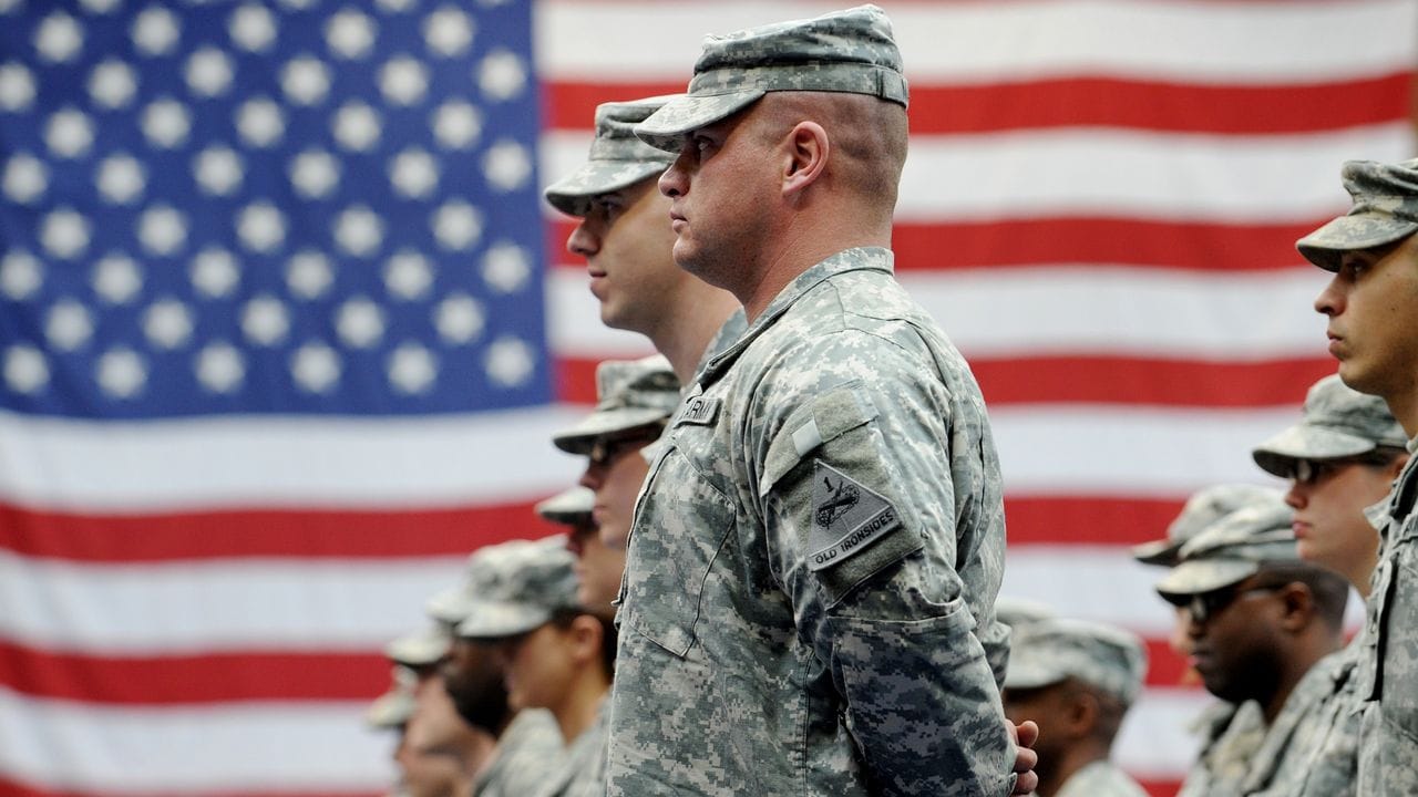 US-Soldaten stehen vor einer US-Flagge.