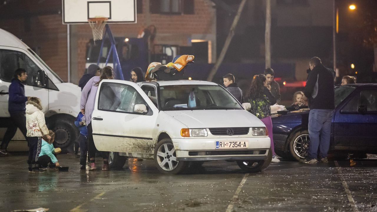 Menschen stehen neben Fahrzeugen, während sie aus Angst vor Nachbeben die Nacht im Freien verbringen.
