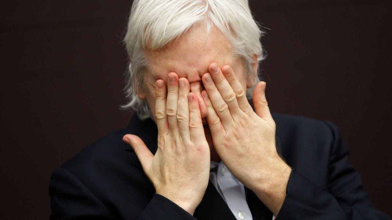 WikiLeaks-Gründer Julian Assange hält die hände vor das Gesicht während einer Pressekonferenz.