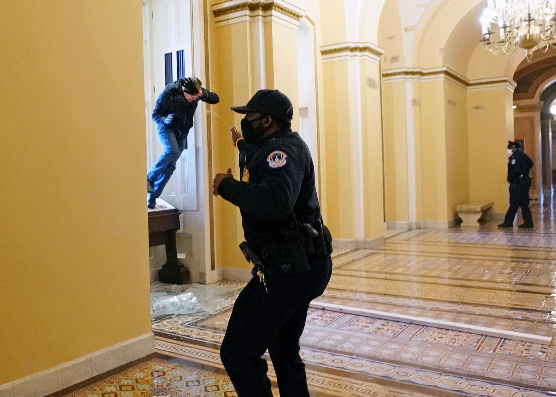 Ein Polizist sprüht Pfefferspray auf eindringende Demonstranten.