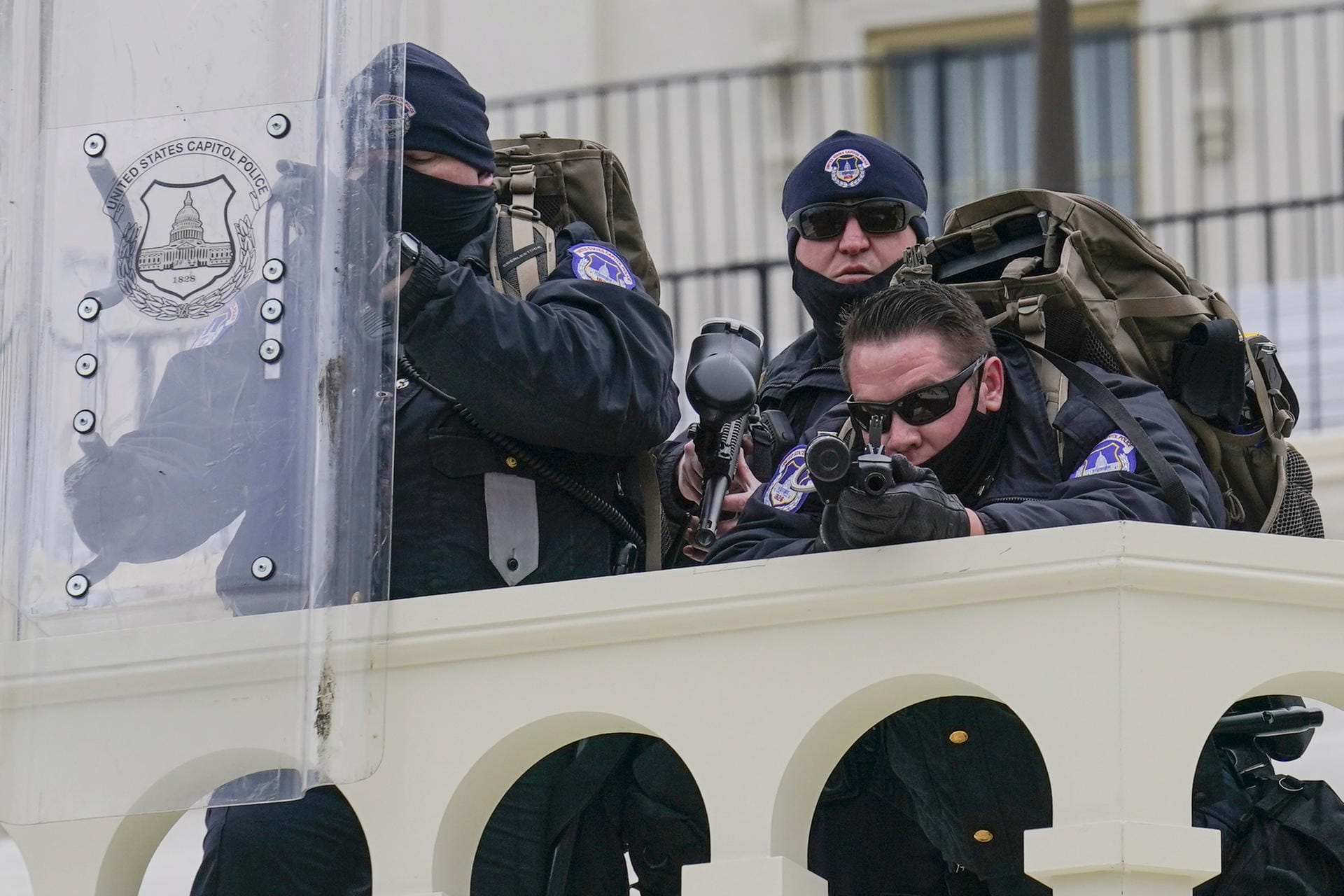 Polizisten mit gezogenen Waffen beobachten das Chaos von einem Balkon im Kapitol. Erst nach mehreren Stunden brachten Sicherheitskräfte die Lage am Parlamentssitz wieder unter ihre Kontrolle.