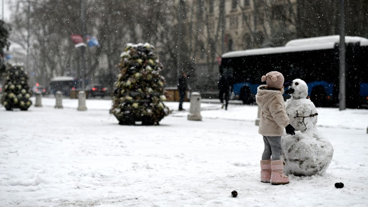 Ein Mädchen baut auf einer Straße in Madrid einen Schneemann.
