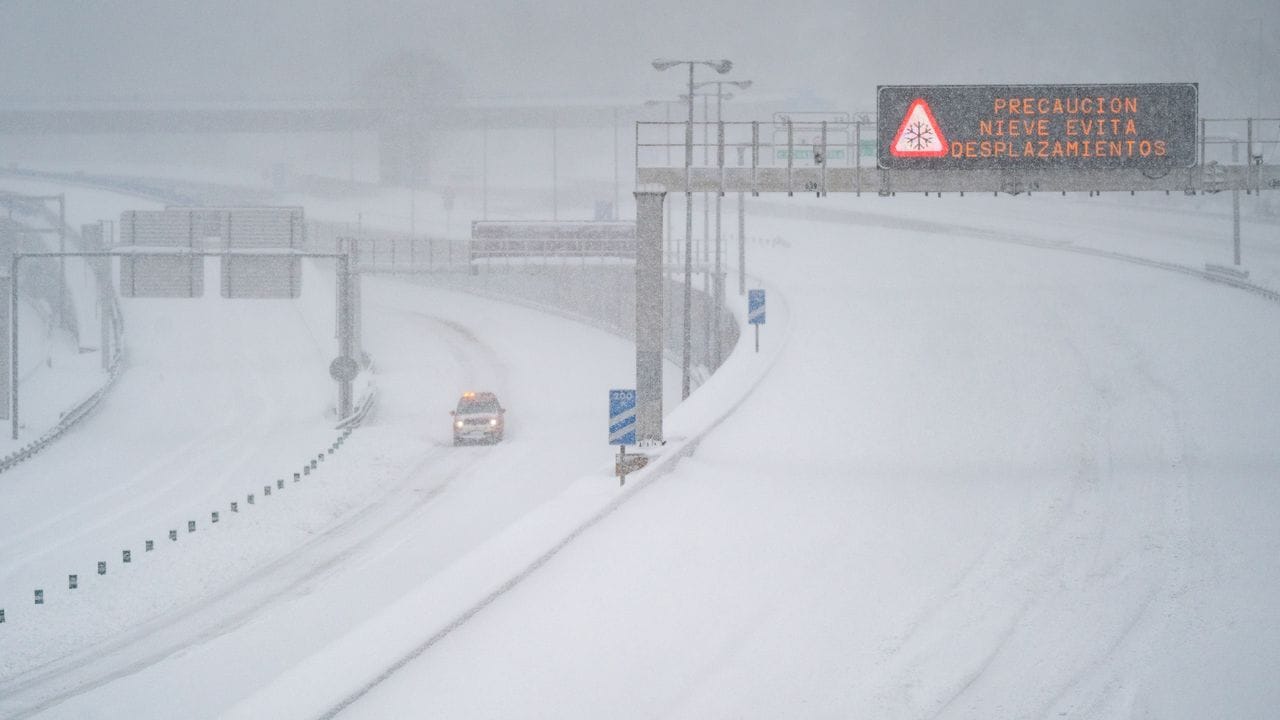 Ein Rettungsfahrzeug fährt auf der leeren, schneebedeckten Schnellstraße M-30 durch Madrid.