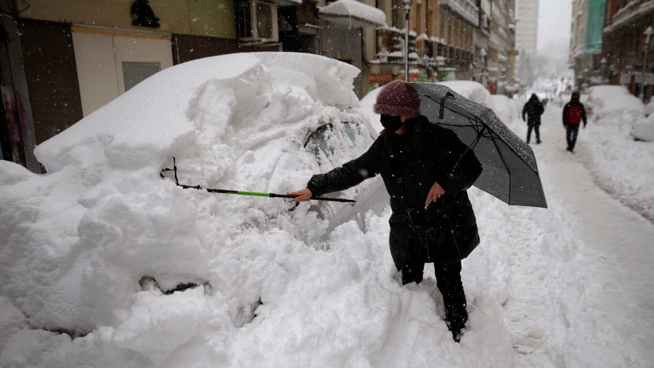 Eine Frau befreit ihr Auto in Madrid vom Schnee.