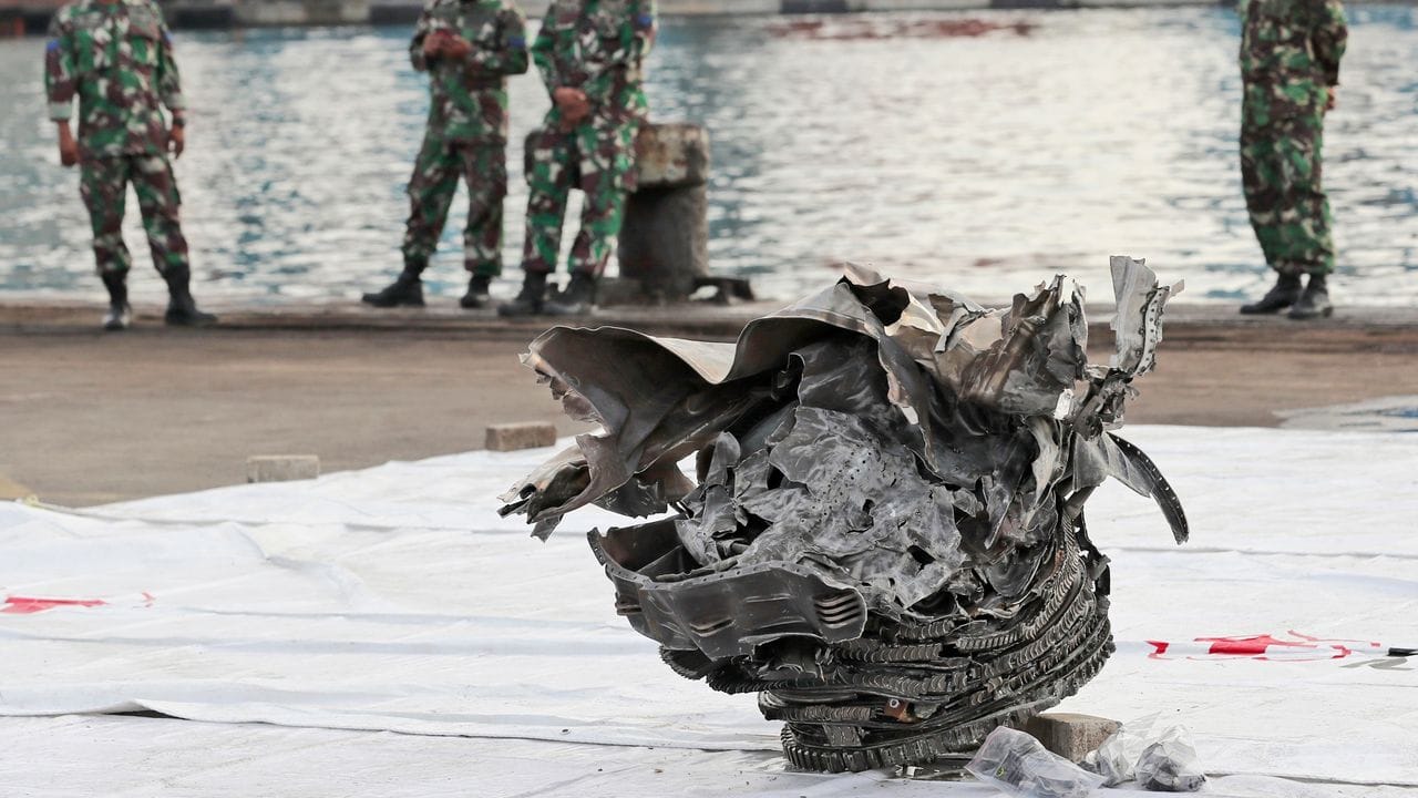 Indonesische Marinesoldaten betrachten ein großes Teil des abgestürzten Flugzeugs der Sriwijaya Air.