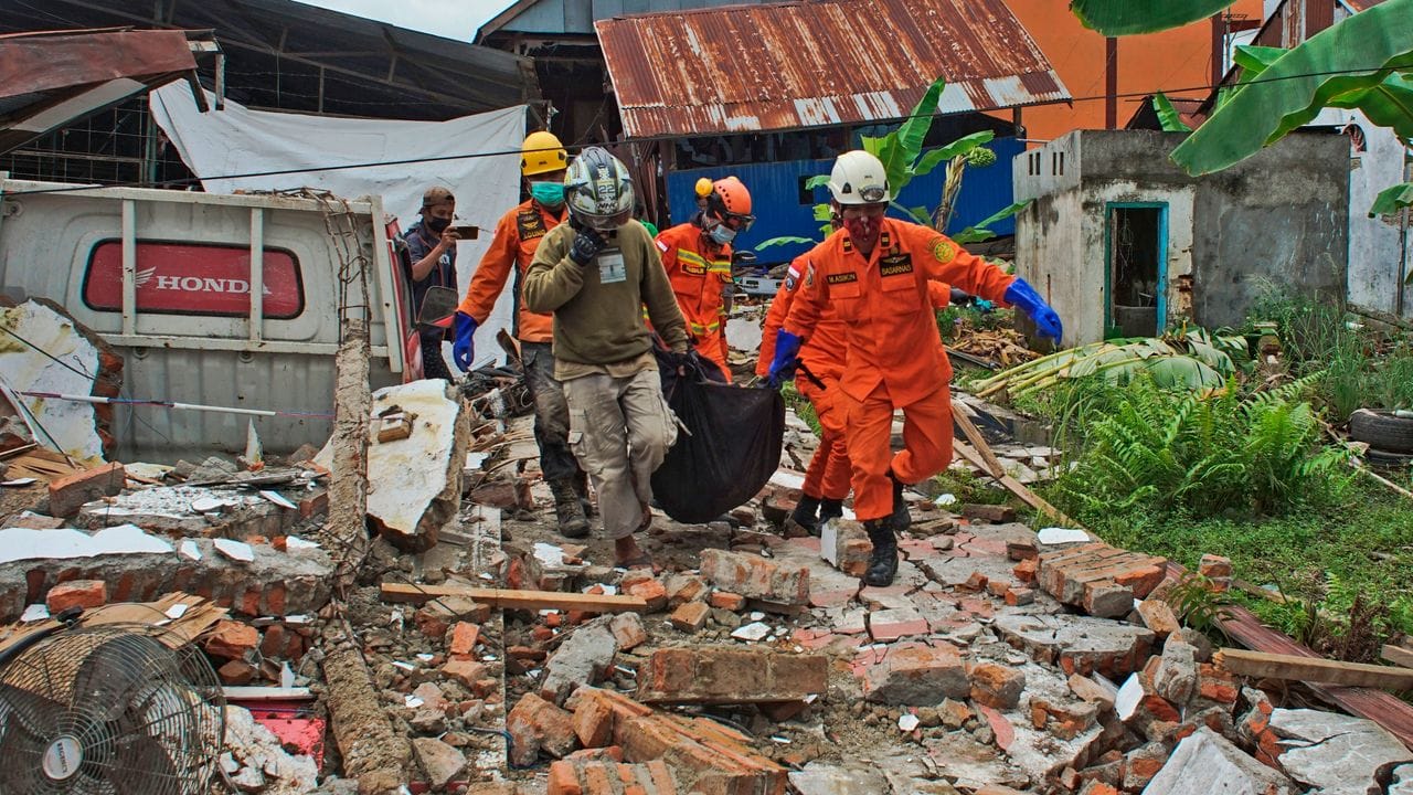 Rettungskräfte tragen in Mamuju einen Leichensack aus den Trümmern.