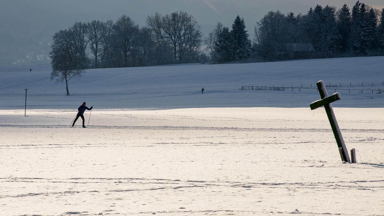 Ein einsamer Langläufer zieht im bayerischen Ettal seine Spur durch die verschneite Gegend.