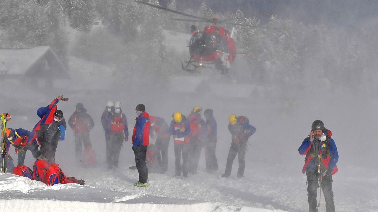 Ein Helikopter landet hinter Helfern der Bergrettung.