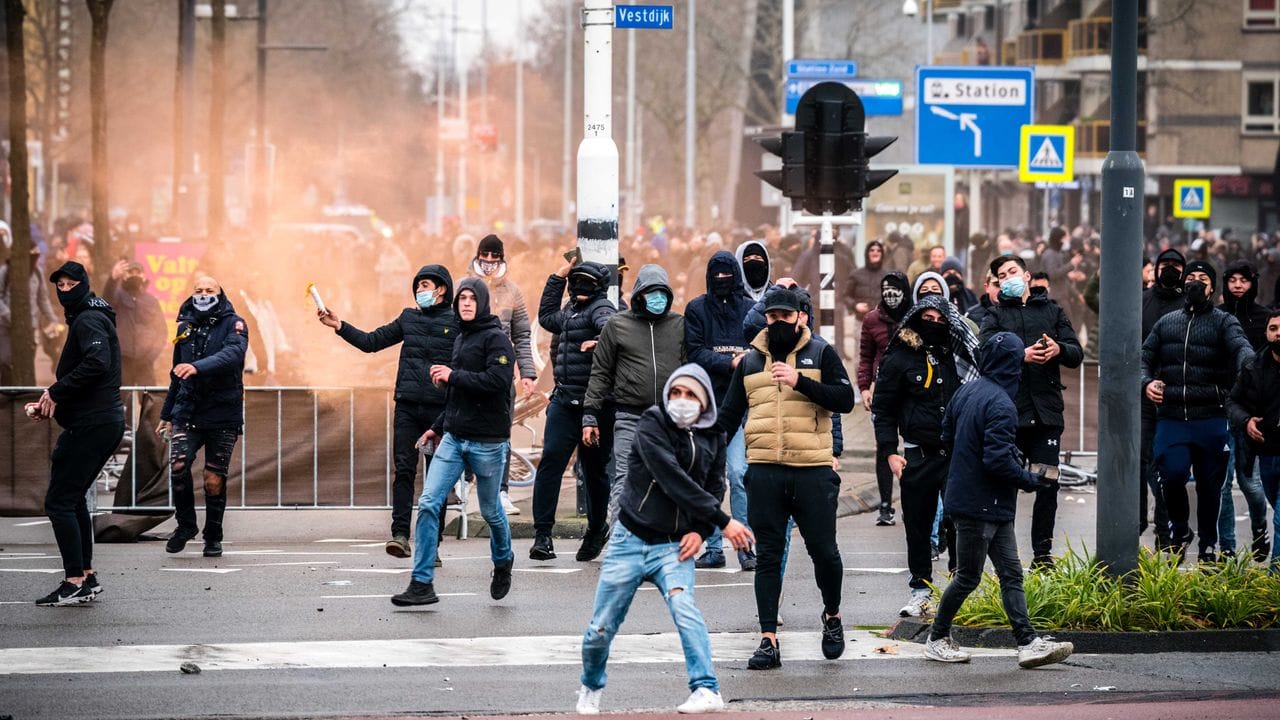 Demonstranten werfen auf einer Straße in Eindhoven mit Steinen.
