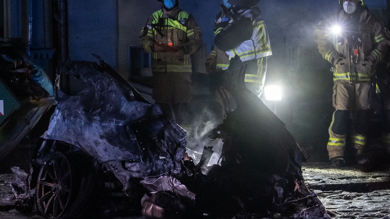 Einsatzkräfte der Feuerwehr stehen am Treptower Park neben dem Autowrack. Einsatzkräfte der Feuerwehr stehen am Treptower Park neben dem Autowrack.