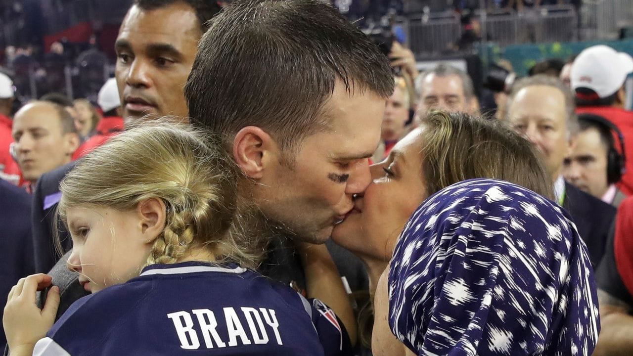 Tom Brady von den New England Patriots hält Tocher Vivian auf dem Arm und küsst seine Frau Gisele Bündchen, die Bradys Mutter Galynn (vorn) den Arm über die Schulter gelegt hat.