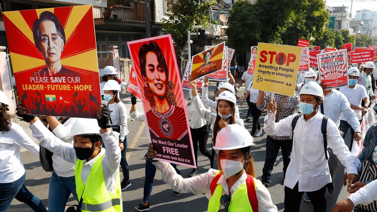 Menschen halten in Mandalay Plakate mit Bilder der abgesetzten Regierungschefin Aung San Suu Kyi, während sie gegen den Militärputsch protestieren.