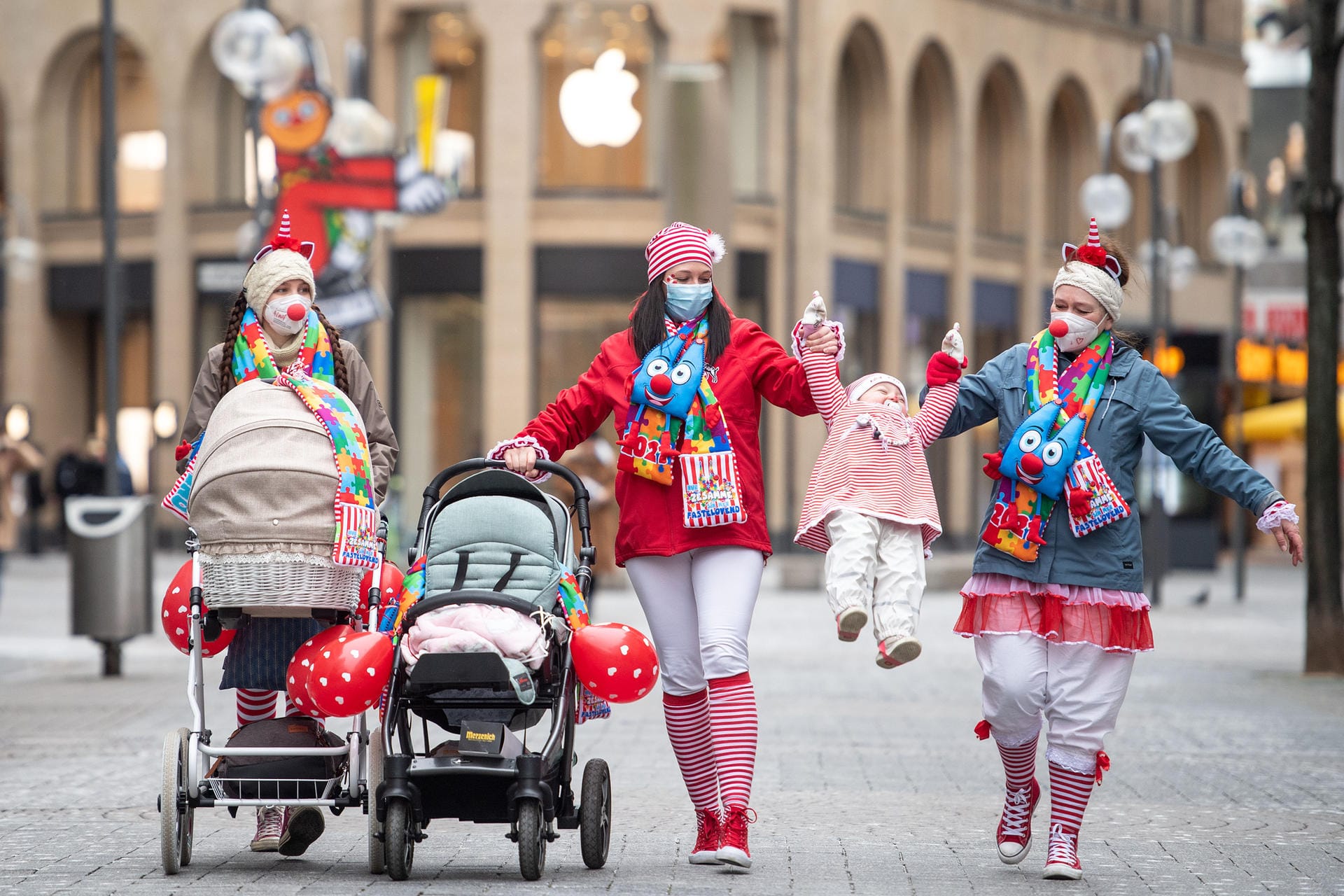 Drei Frauen laufen mit Kinderwagen und einem kleinen Mädchen verkleidet auf der Schildergasse, auf der normalerweise der Rosenmontagszug verläuft.