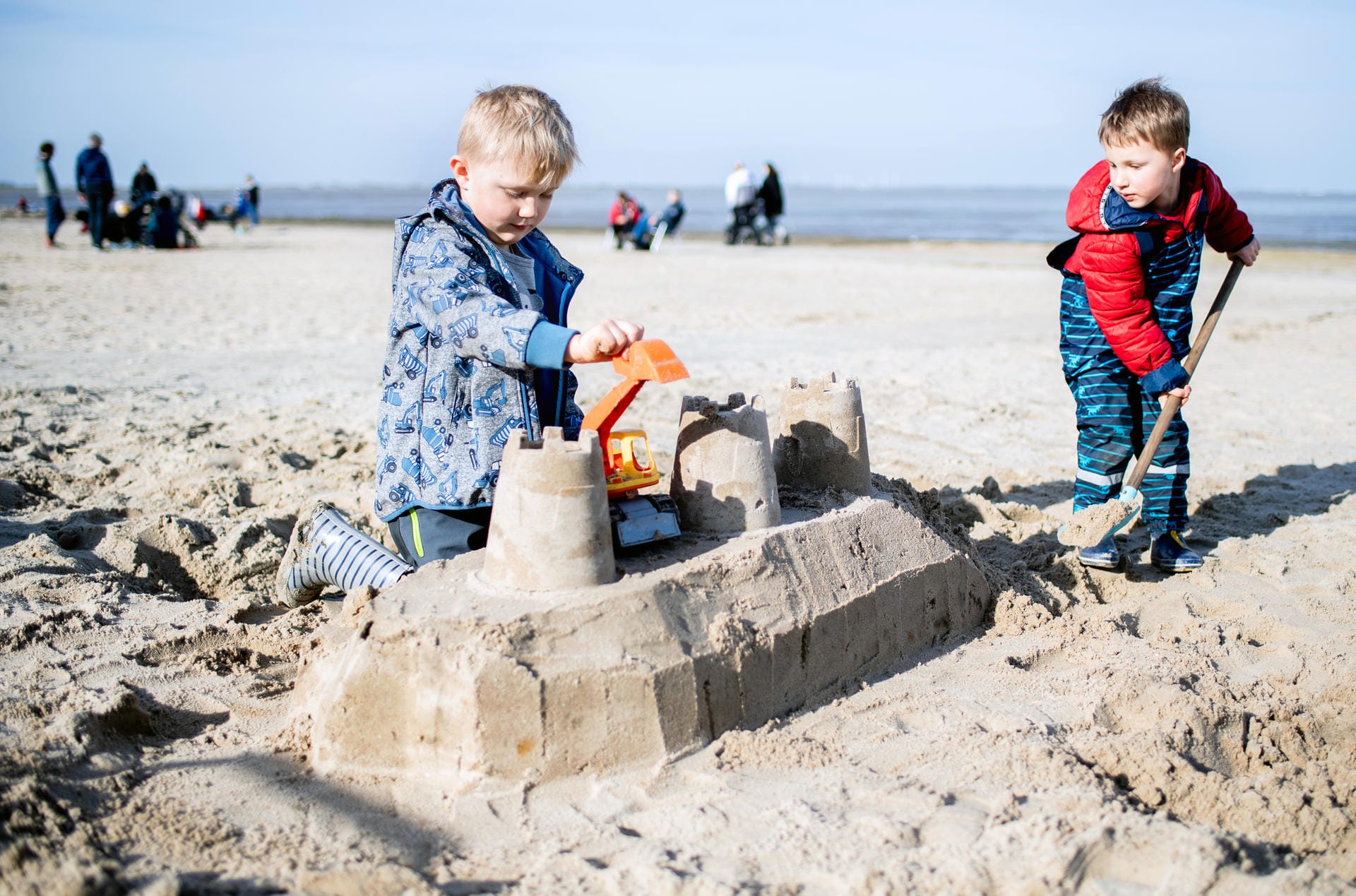 Dangast in Niedersachsen: Die Geschwister Noah (links) und Emil bauen bei sonnigem Wetter eine Sandburg am Strand.