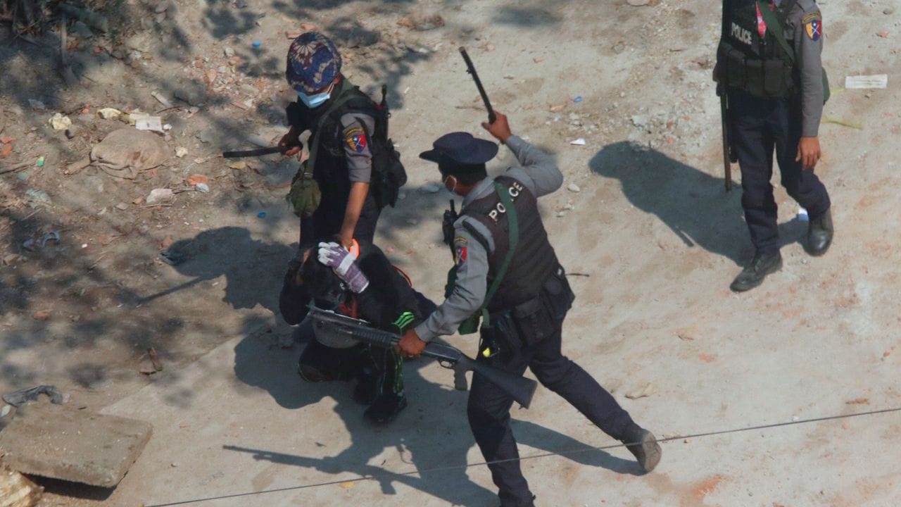 Polizisten schlagen mit Knüppeln auf einen Demonstranten am Stadtrand von Yangon (ehemals Rangoon) ein.