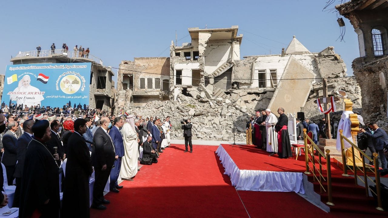 Zwischen von Granaten zerstörten Gebäuden nimmt Papst Franziskus an einem Gebet für die Opfer des Krieges teil.
