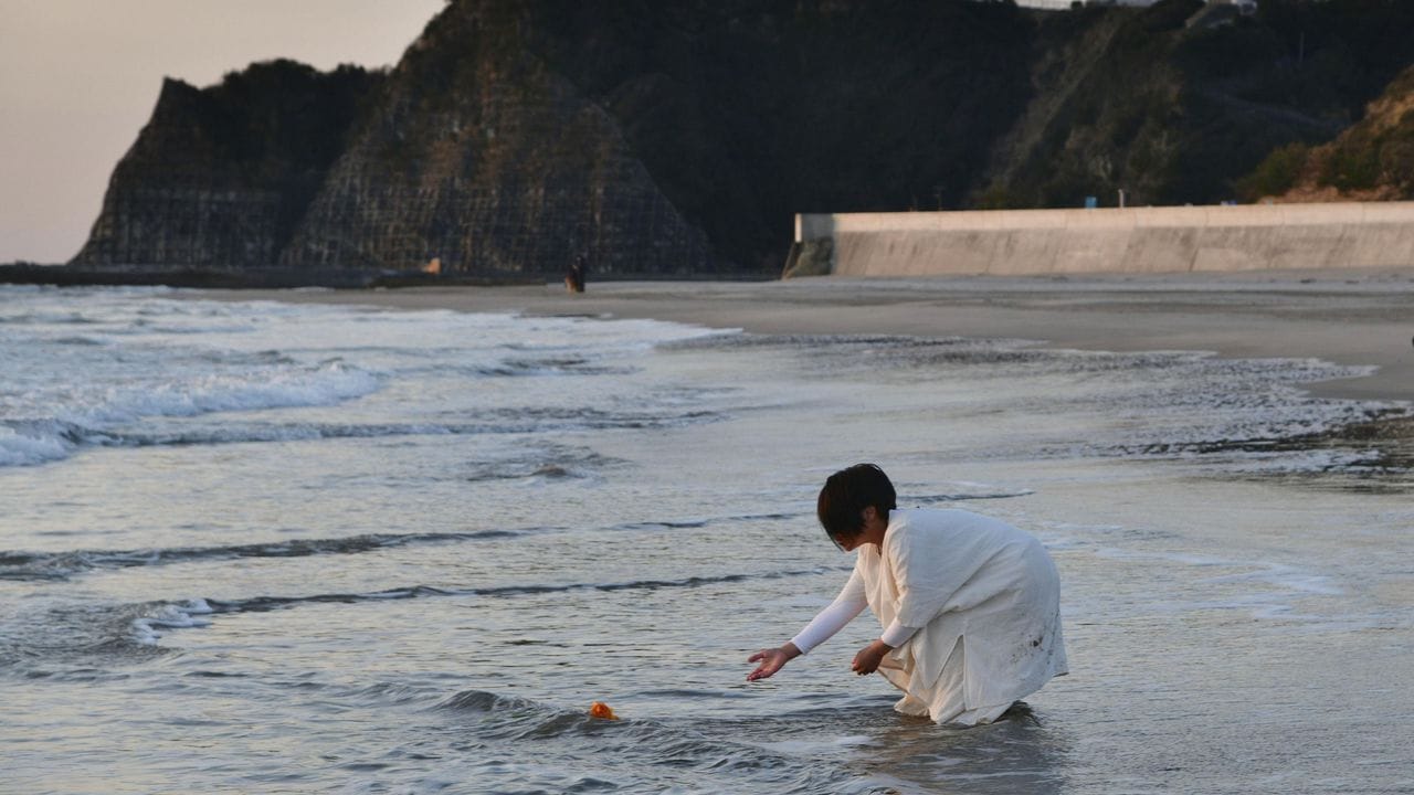 Eine Frau legt in Gedenken an die Opfer der Fukushima-Katastrophe Blumen an einem Strand in der nordostjapanischen Stadt Iwaki ab.
