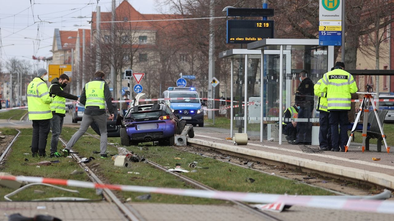 Einsatzkräfte der Polizei und Sachverständige sind an der Unfallstelle neben dem Unfallwagen im Gleisbett der Straßenbahn im Einsatz. Einsatzkräfte der Polizei und Sachverständige sind an der Unfallstelle neben dem Unfallwagen im Gleisbett der Straßenbahn im Einsatz.
