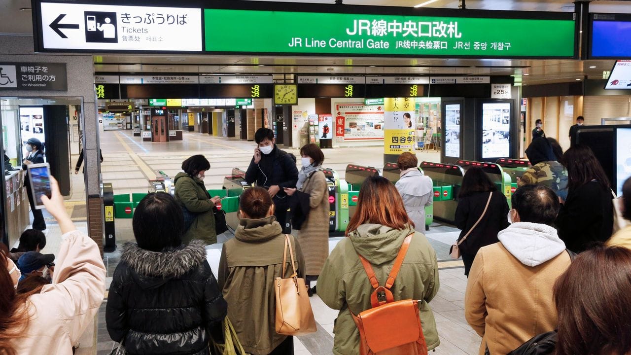 Menschen warten an einem Bahnhof in Sendai, der Zugverkehr wurde nach einem Erdbeben eingestellt.