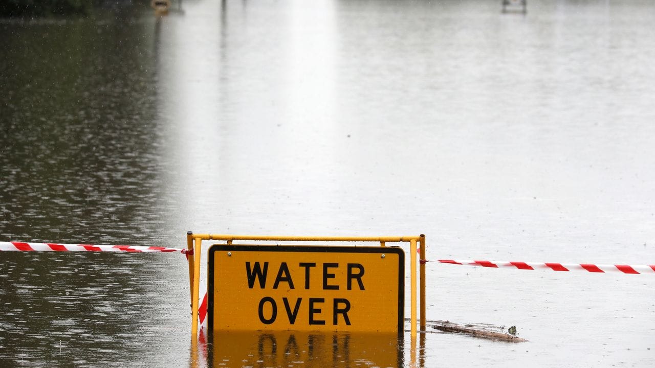 Ein Schild mit Warnhinweis auf einer überfluteten Straße bei Windsor.