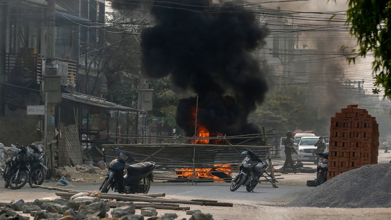 Bewaffnete Polizisten und Soldaten aus Myanmar erreichen eine Barrikade, die von Putschgegnern in Mandalay errichtet wurde.