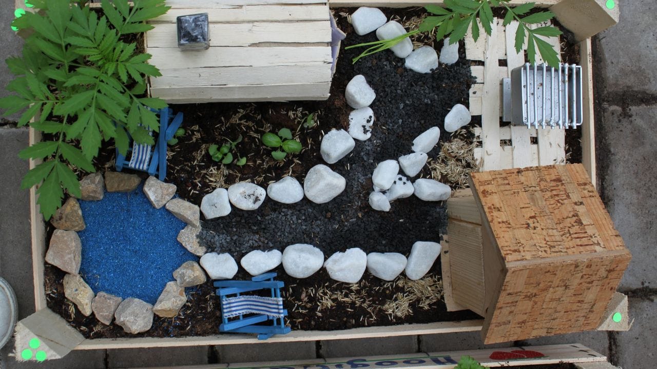 Fertig ist der Mini-Garten: Mit kleinen Steinen, Holzmöbeln und einem Teich können Kinder ihr kleines Paradies verschönern.