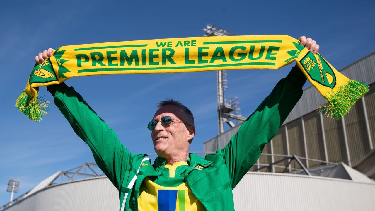 Ein Fan von Norwich City feiert vor dem Stadion über den Aufsteig in die Premier League.
